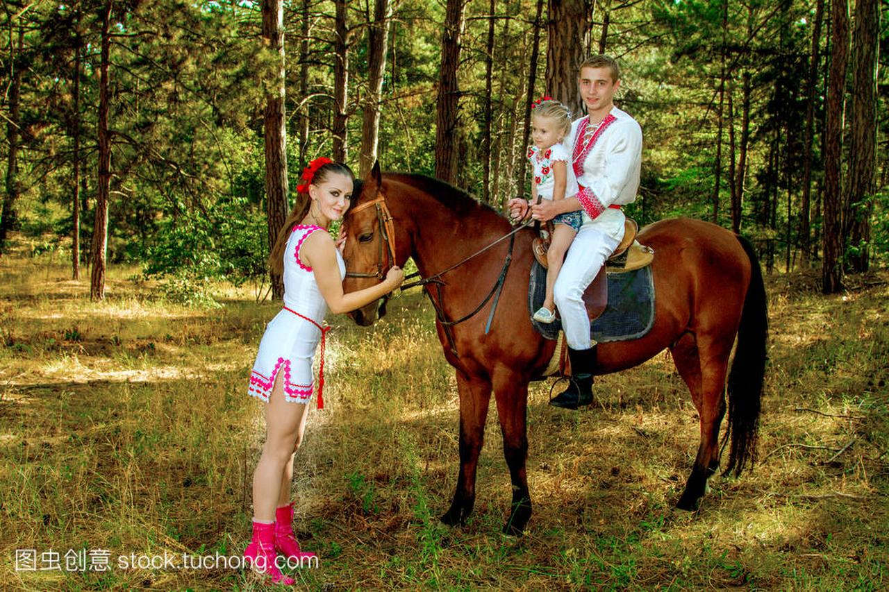 乌克兰人妈妈和爸爸的女儿在树林里骑在马背上