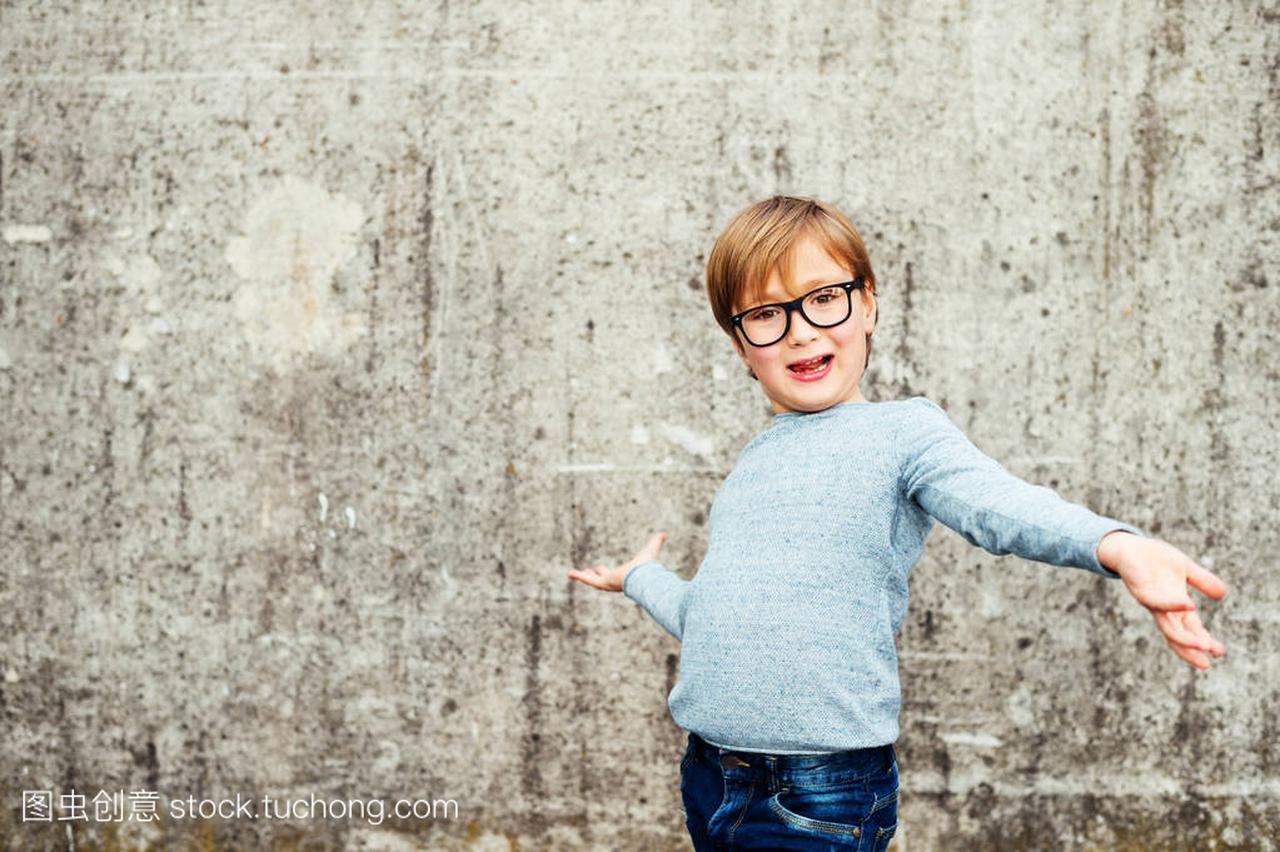 一个可爱的小男孩,戴着眼镜、 淡蓝色套头衫和