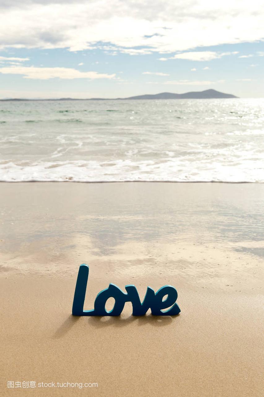 在与波浪在海滩的沙子蓝色的木制的爱情词