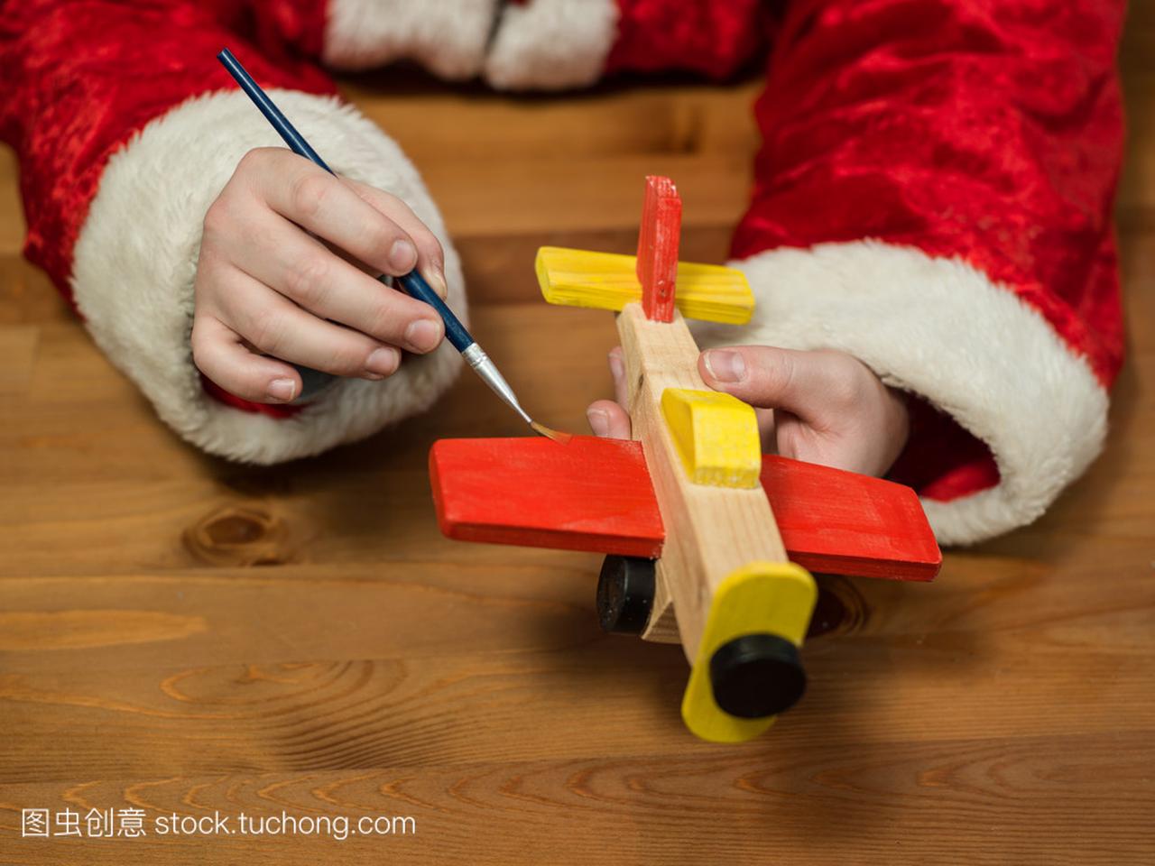 圣诞老人坐在他的工作室绘画玩具飞机。鹤