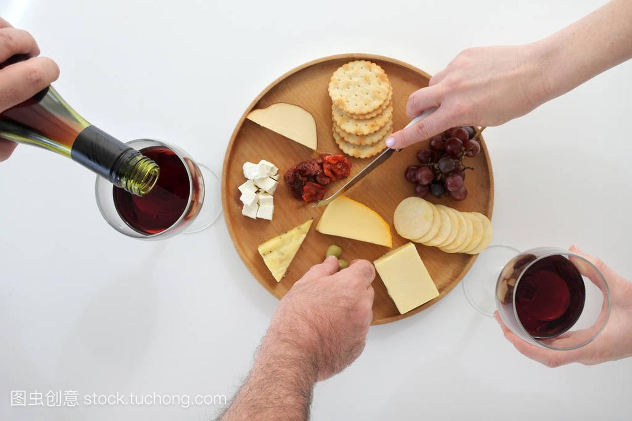 男人和女人喝红酒,吃从奶酪拼盘
