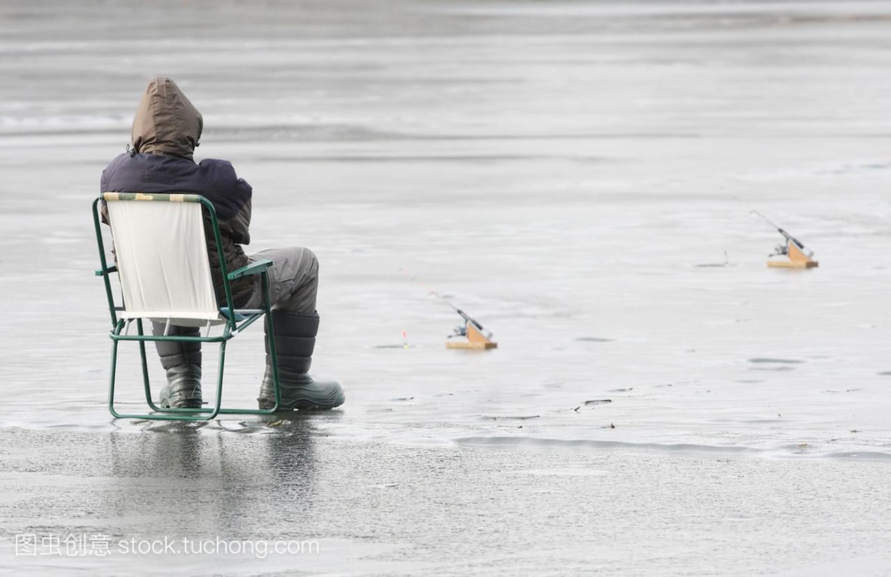 年轻的渔夫,在冬天结冰的湖面上抓一条鱼
