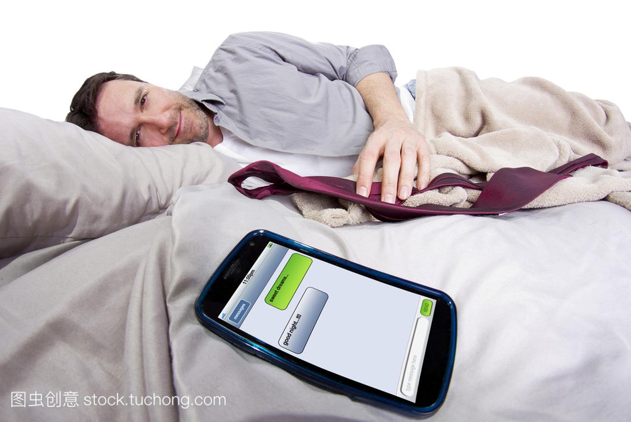 手机屏幕显示文本的邮件,而男性是躺在床上