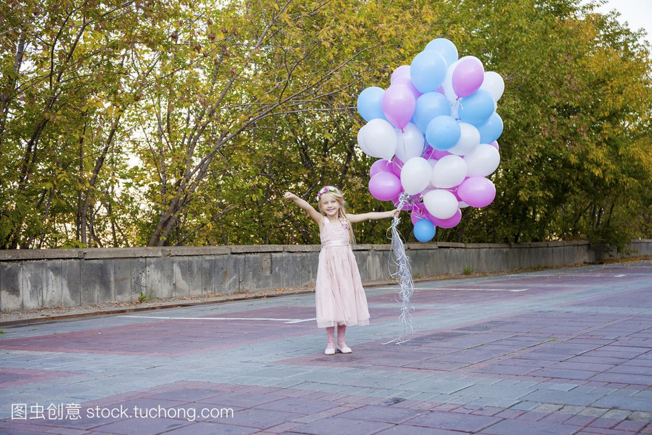 小五岁女孩穿着粉红色的连衣裙拿着气球
