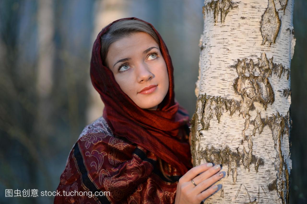 俄罗斯姑娘在一条围巾在白桦林