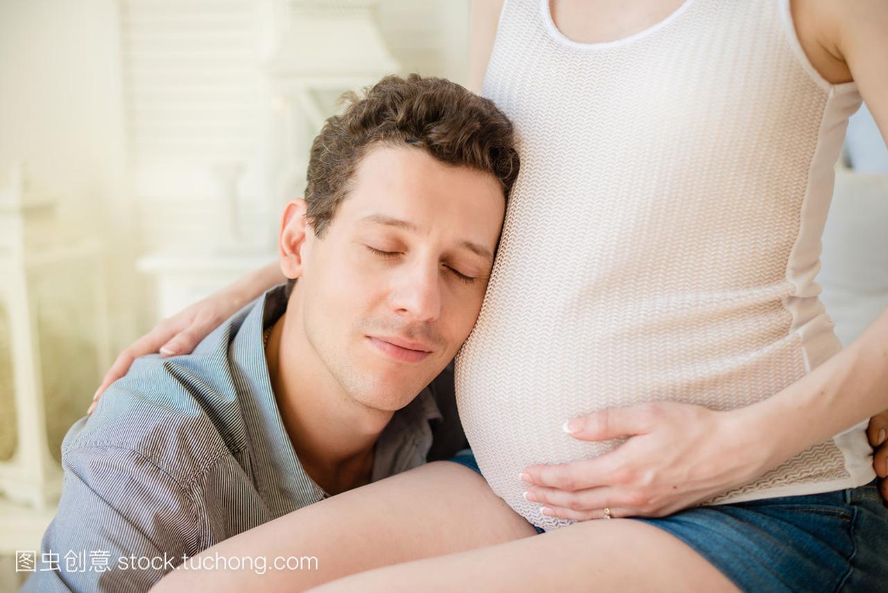 丈夫拥抱他怀孕的妻子的肚子