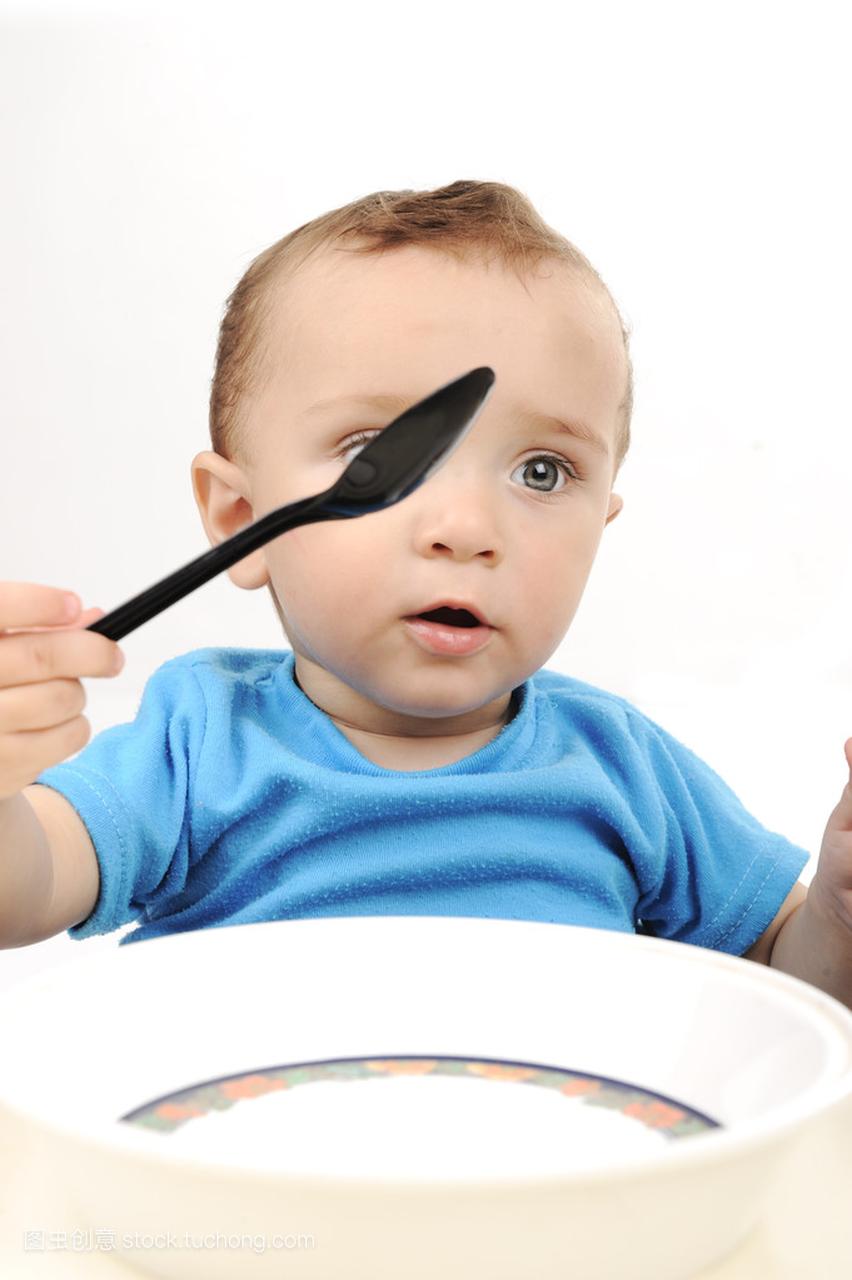 可爱可爱一岁宝宝吃桌上的绿眼睛、 勺和