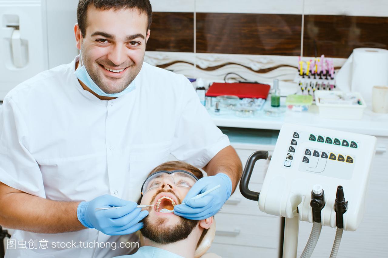 快乐牙医治疗的年轻人病人的牙齿