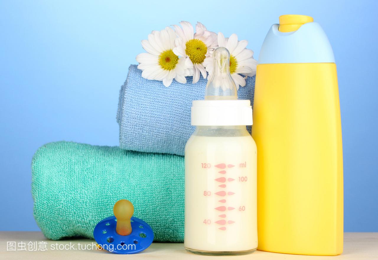 婴儿奶瓶的牛奶和洗发水附近毛巾上的蓝色背景