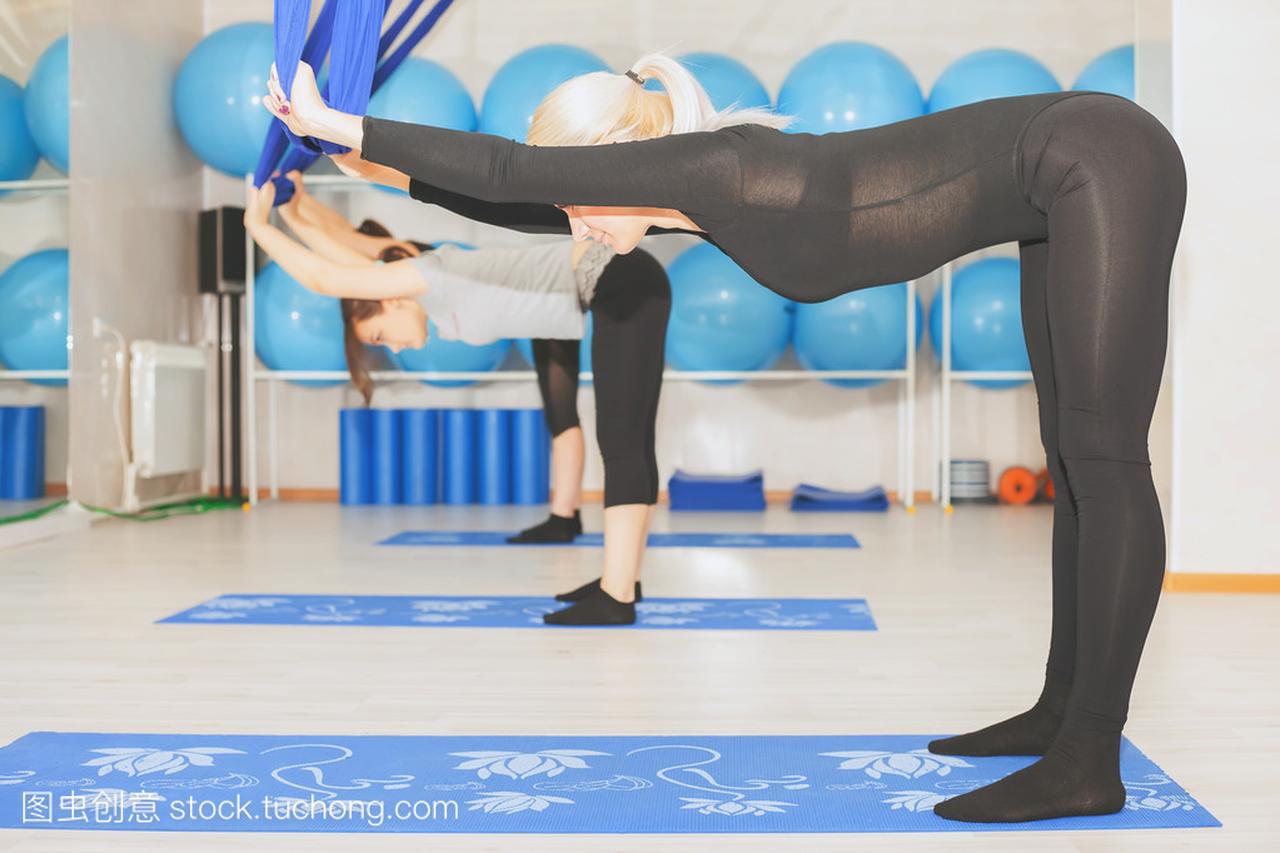年轻妇女做空中瑜伽锻炼或反重力瑜伽