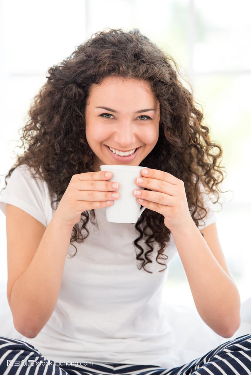 微笑的女士有早晨喝咖啡或茶