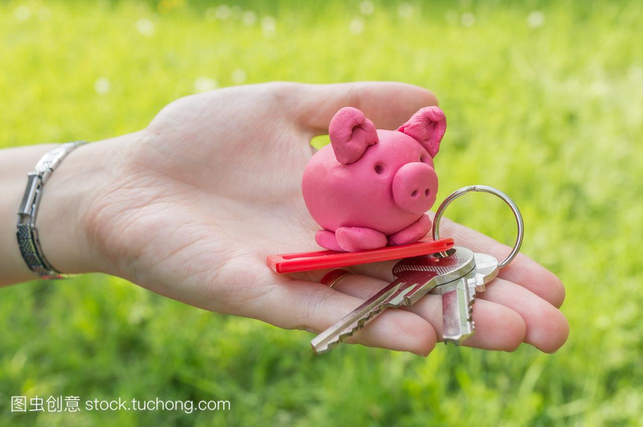 手拿着小猪和密钥作为储蓄和抵押贷款的象征
