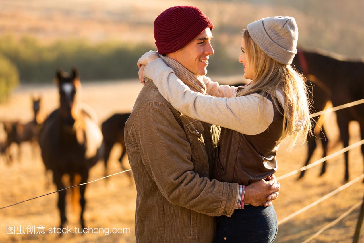 浪漫的年轻情侣在马的农场里