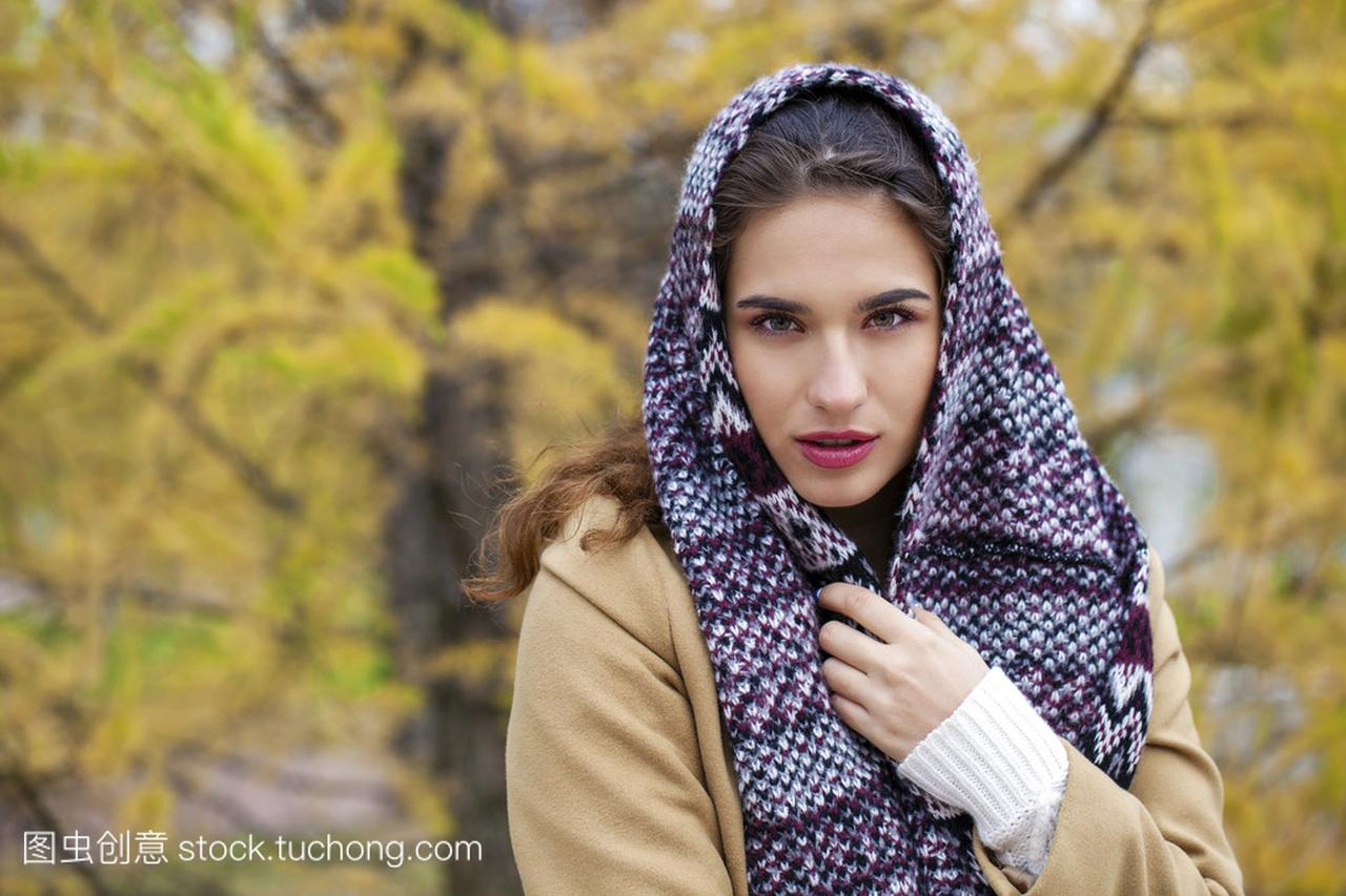 年轻的意大利人在米色大衣和织一条围巾在她头