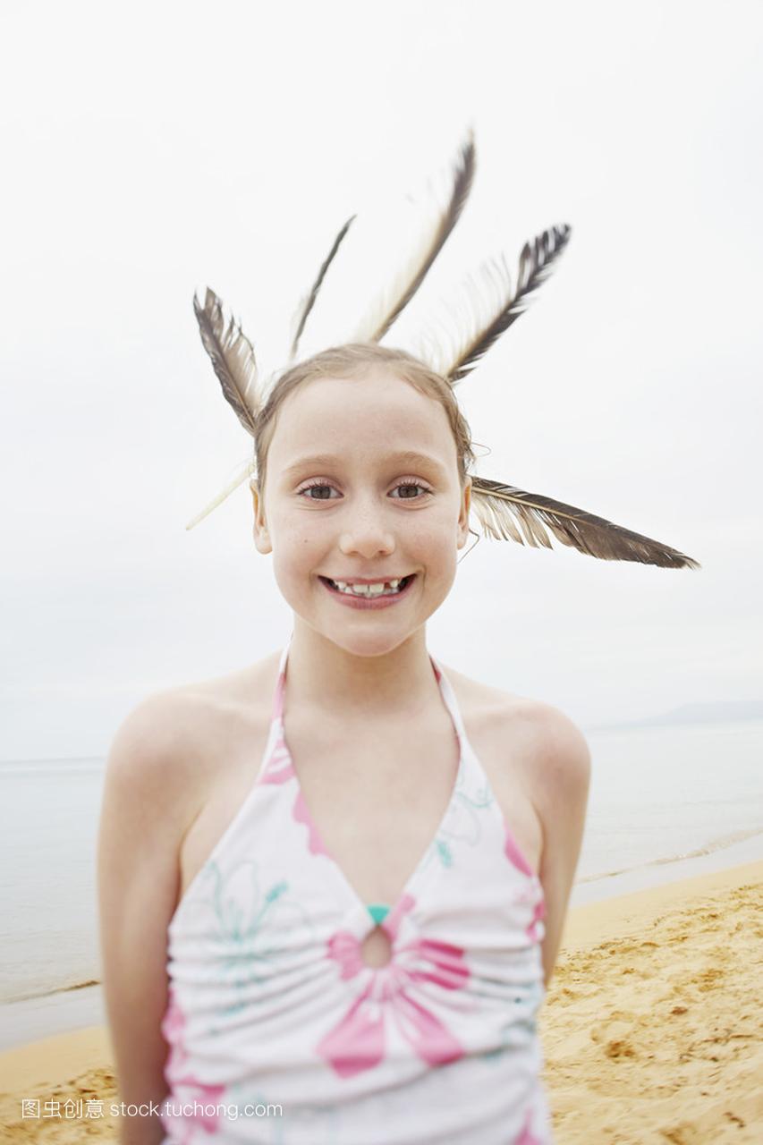 长着羽毛的头发在海滩上的女孩