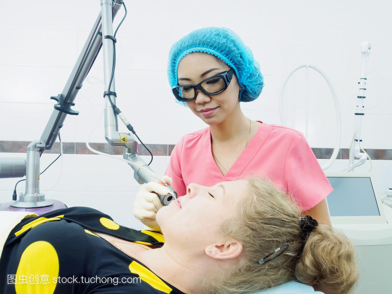 年轻的亚洲医生女人向病人激光皮肤磨削术在医