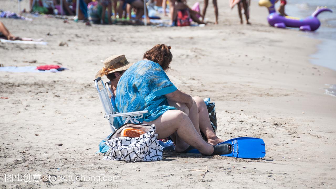 坐在海边沙滩上的胖女人