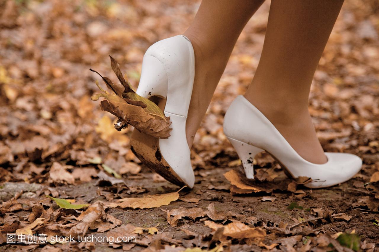 女人的腿在白鞋上的落叶