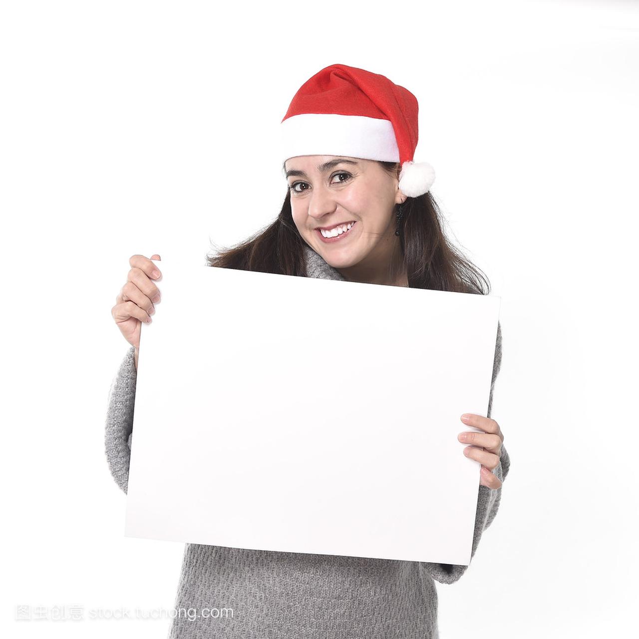 年轻甜美拉丁女人在圣诞老人帽子拿空白广告牌