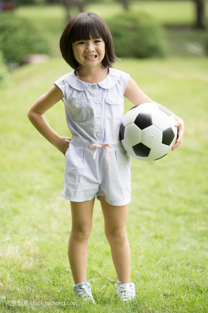 小的亚洲女孩在公园里踢足球