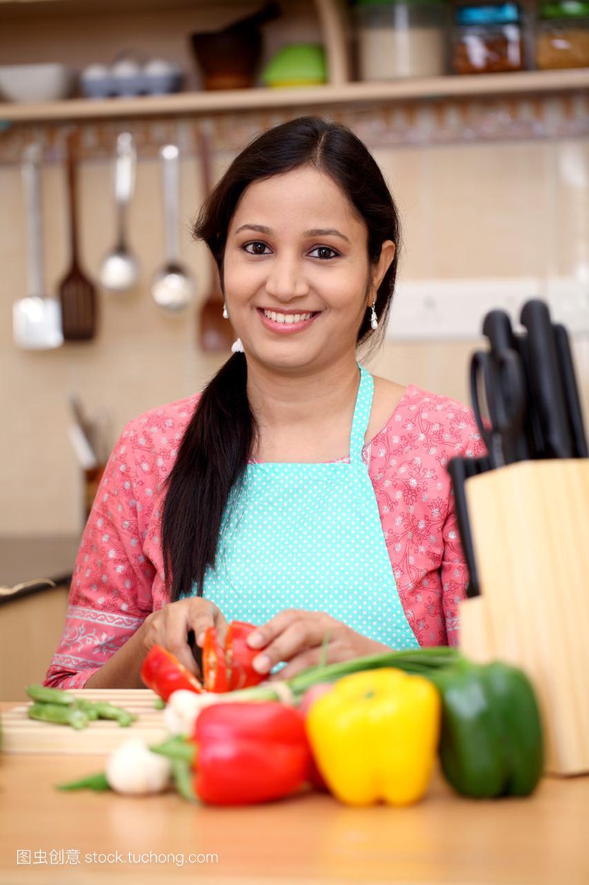 微笑的年轻印度女士在她的厨房