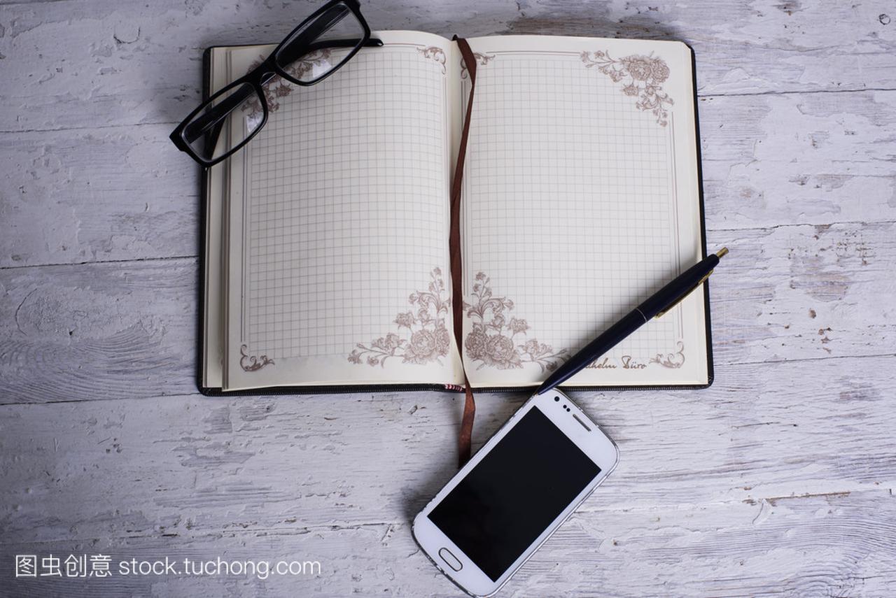 记事本、 手机、 眼镜和笔在白色的木制背景上