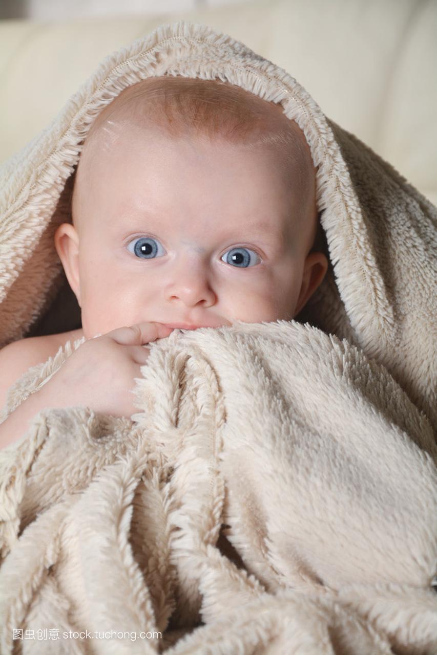 用一条毛巾后淋浴在家里的床上的婴儿