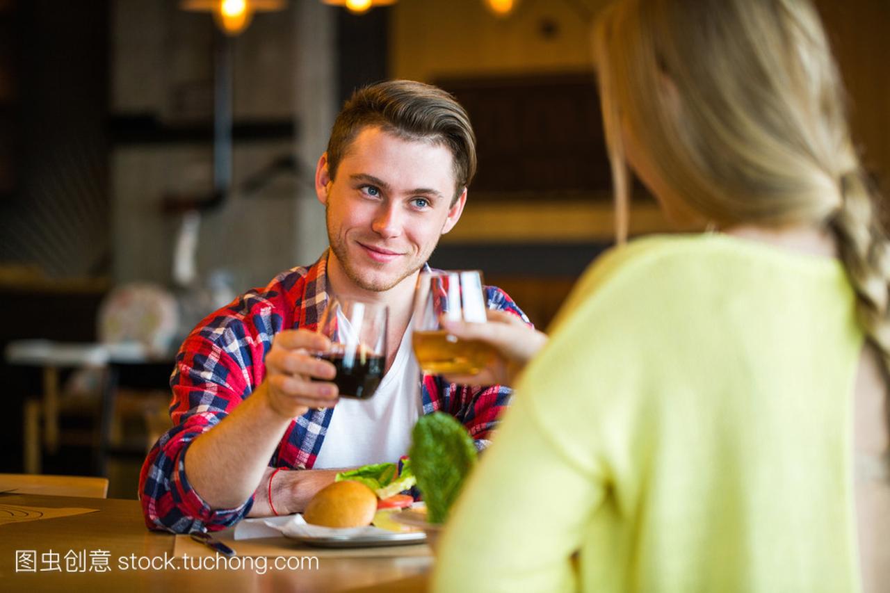 年轻的男人和女人在一家餐馆喝葡萄酒。年轻的