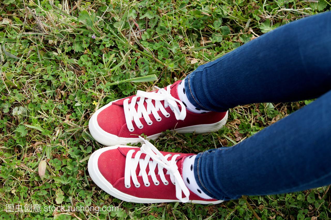 红色运动鞋踩草的女人