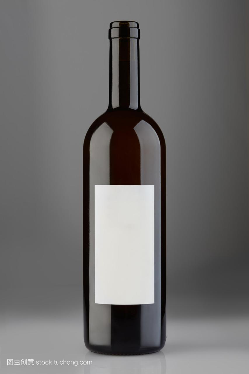 用灰色的背景上的空白标签打开红酒瓶