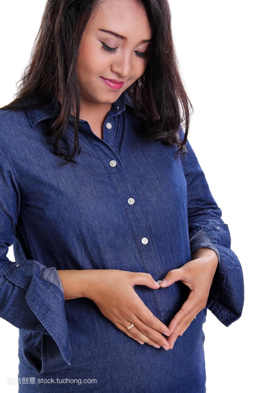 怀孕的妇女在她的肚子上制作心的形状