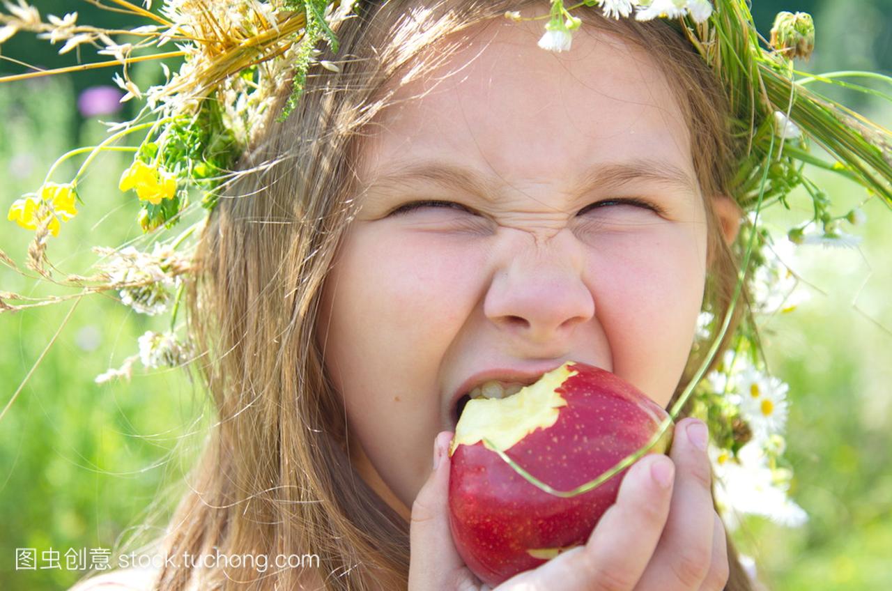 小小快乐的女孩,在夏日一天吃一个大的红苹果