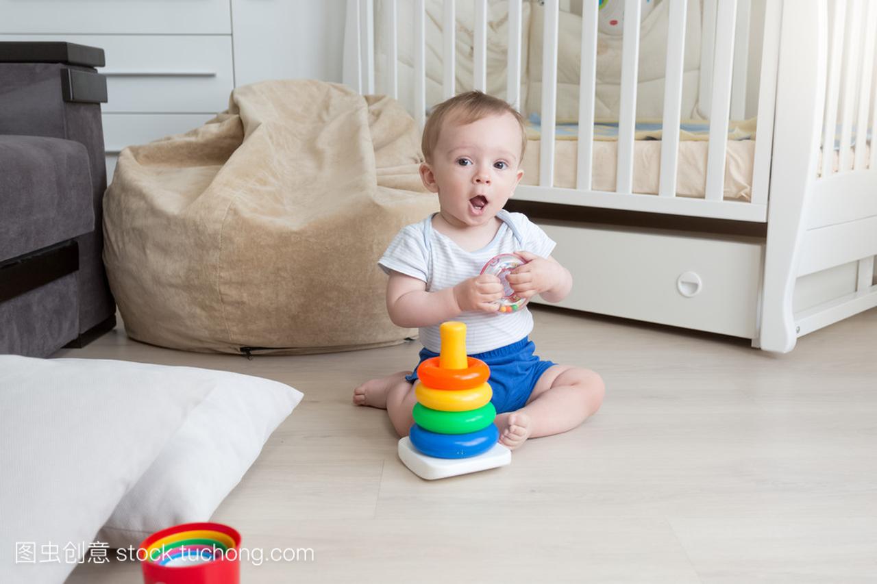 9 个月大婴儿在地板上玩和组装玩具塔