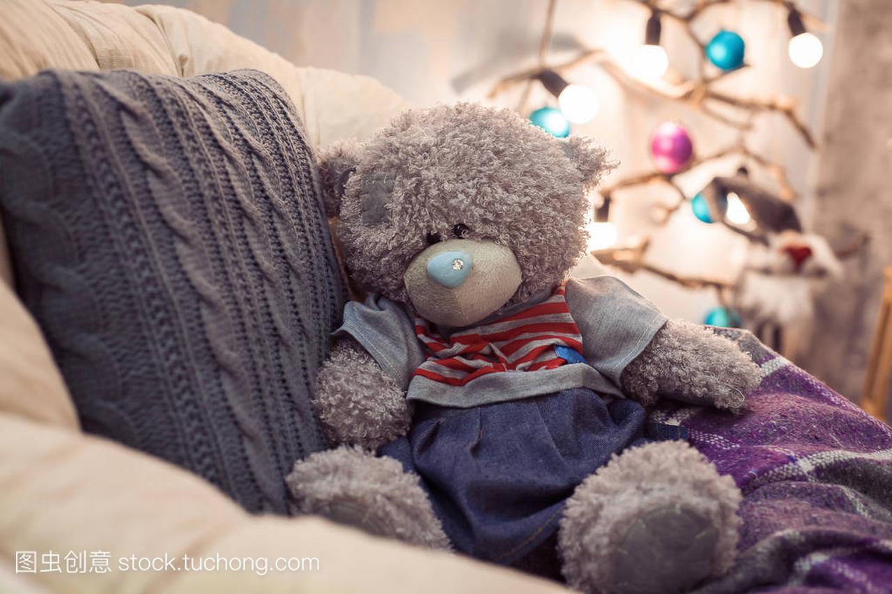玩具熊坐在椅子上用灰色的枕头