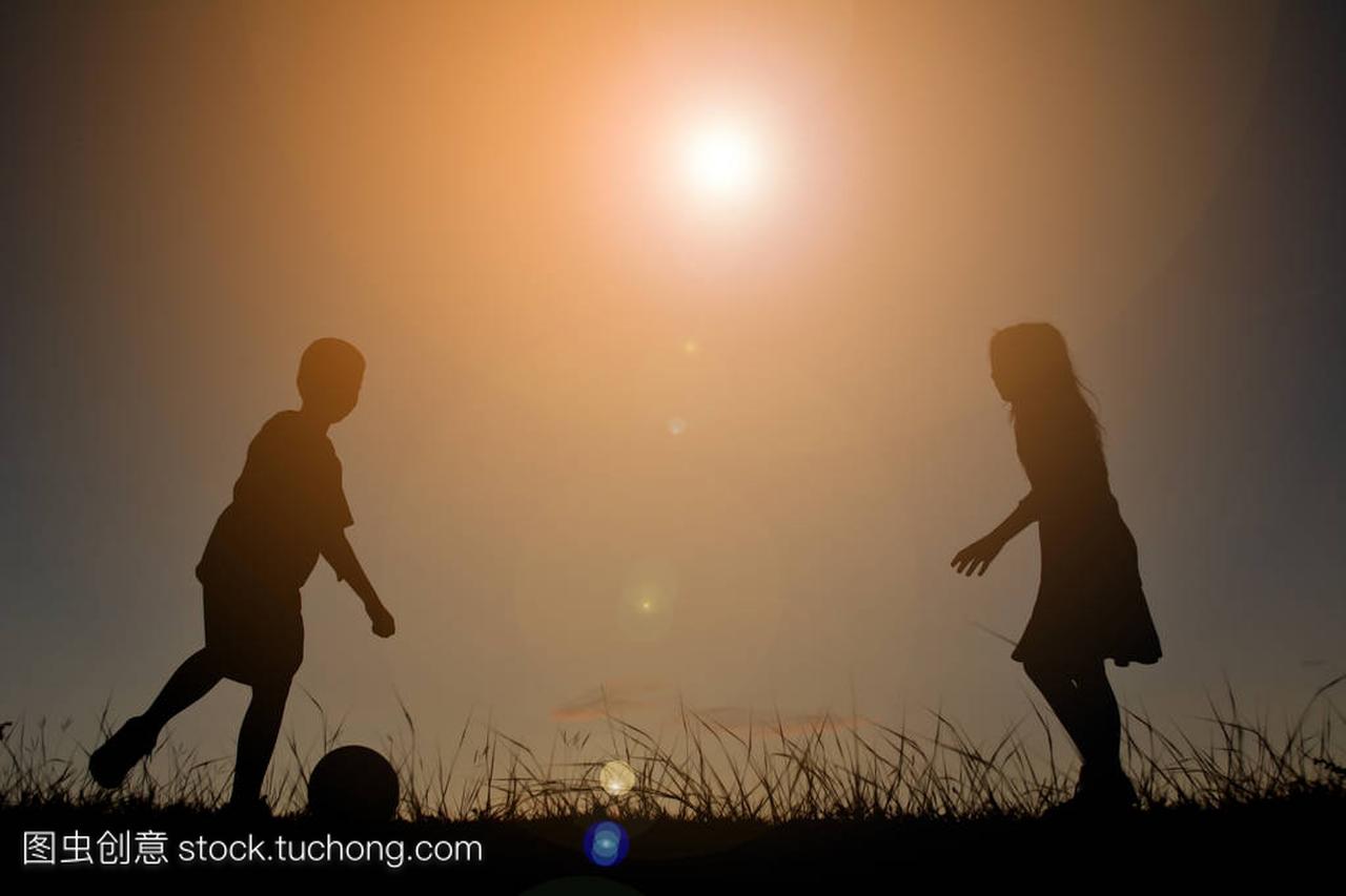 剪影孩子天空日落在踢足球。假日的时间