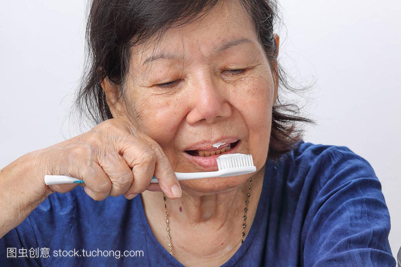 亚洲老妇尝试使用牙刷,手震颤
