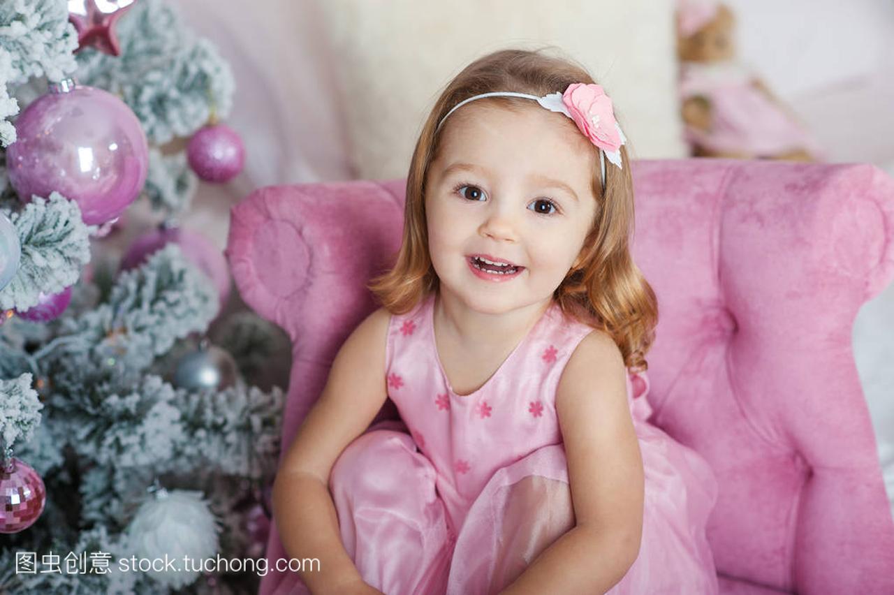 漂亮的金发小姑娘棕色的眼睛,微笑着圣诞树的