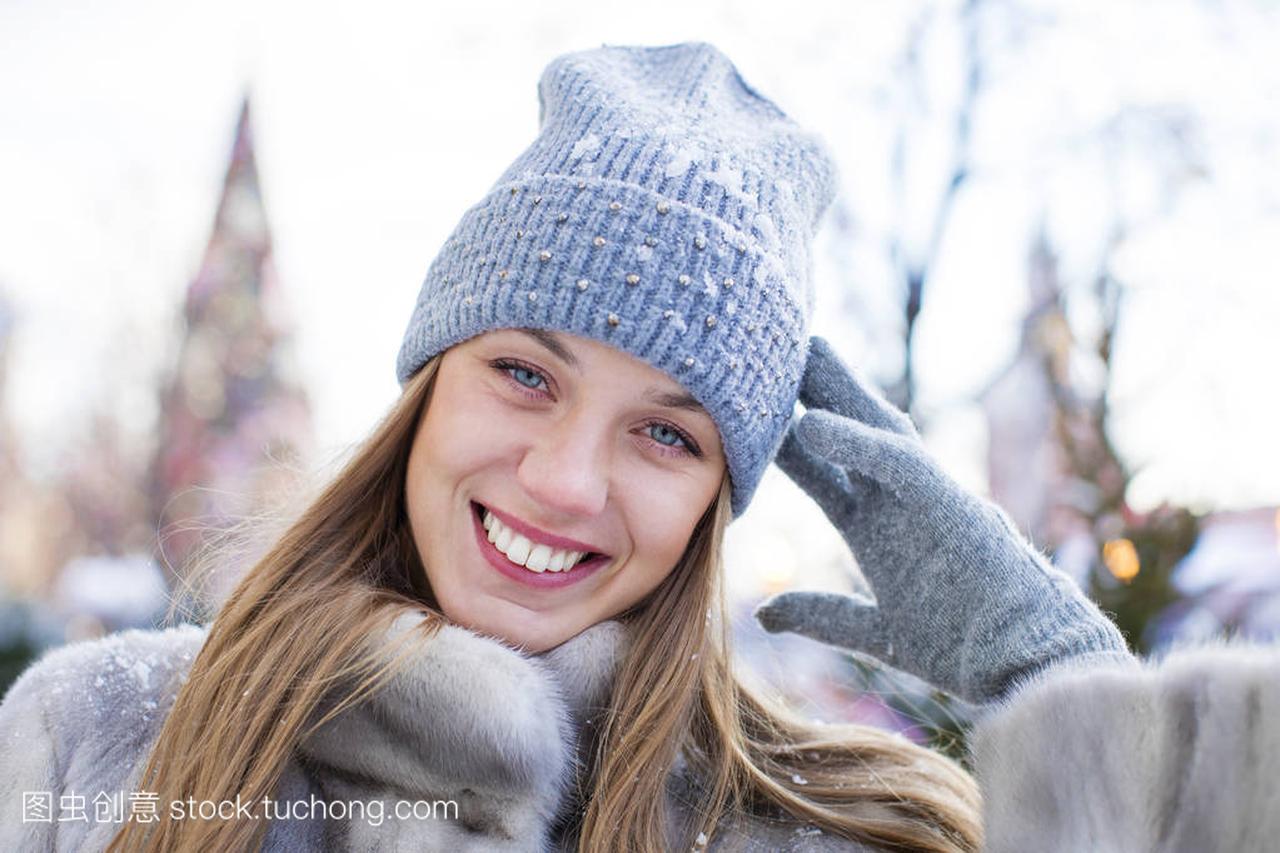 蓝色针织的帽子和灰色貂皮大衣的年轻女子