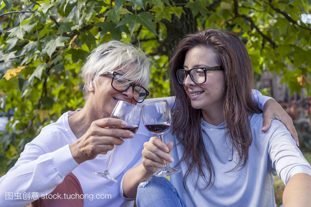 母亲和成年女儿品尝红酒坐在一棵大树