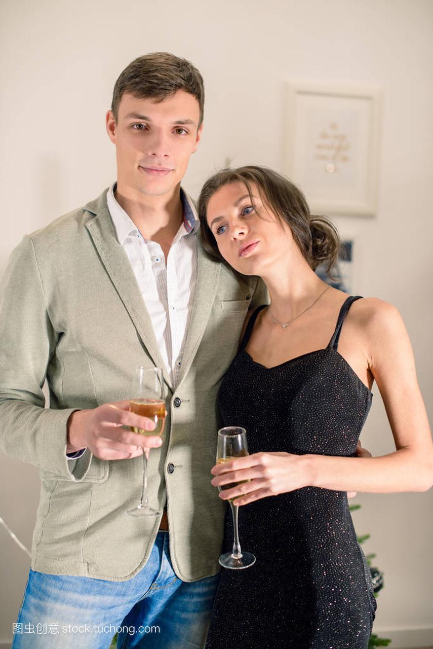 美丽的年轻夫妇拿着杯香槟和 smili