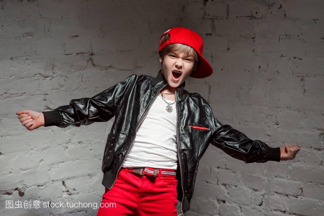 酷年轻嘻哈男孩在顶红色的帽子和红色的裤子和
