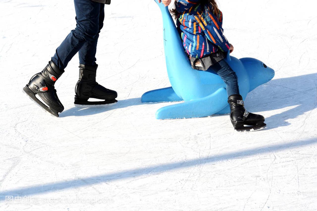 在室外溜冰场,孩子学习滑冰与塑料密封作为培