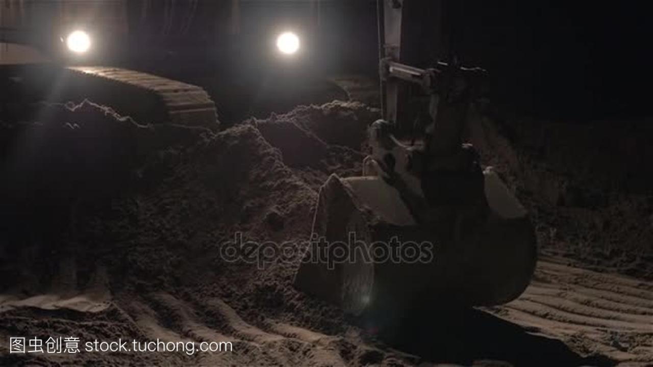 挖掘机挖沙子和尘土夜班期间道路工程,近摄镜
