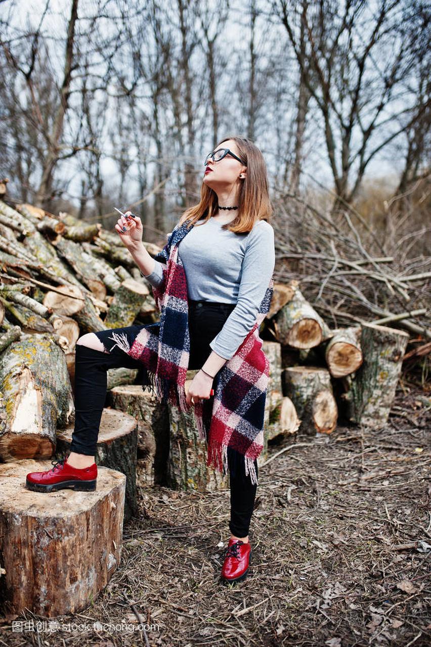 年轻女孩吸烟室外背景木树桩
