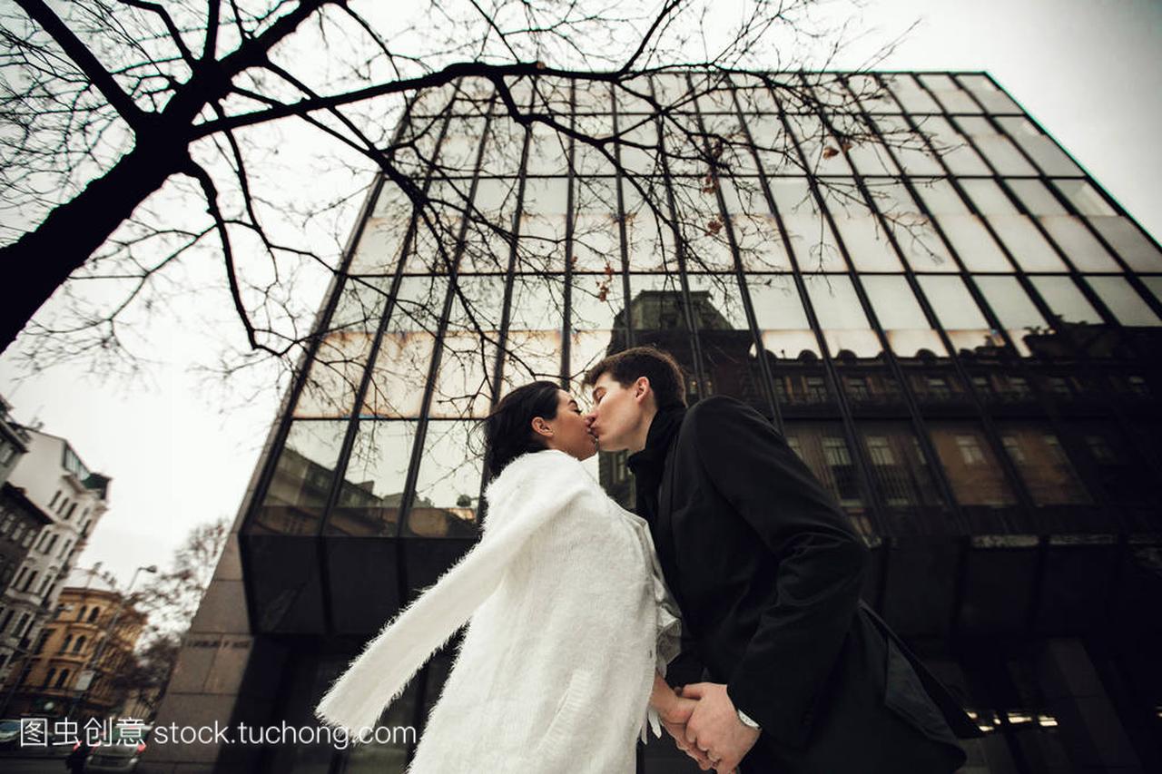 新婚夫妇在一个巨大的玻璃大厦下亲吻