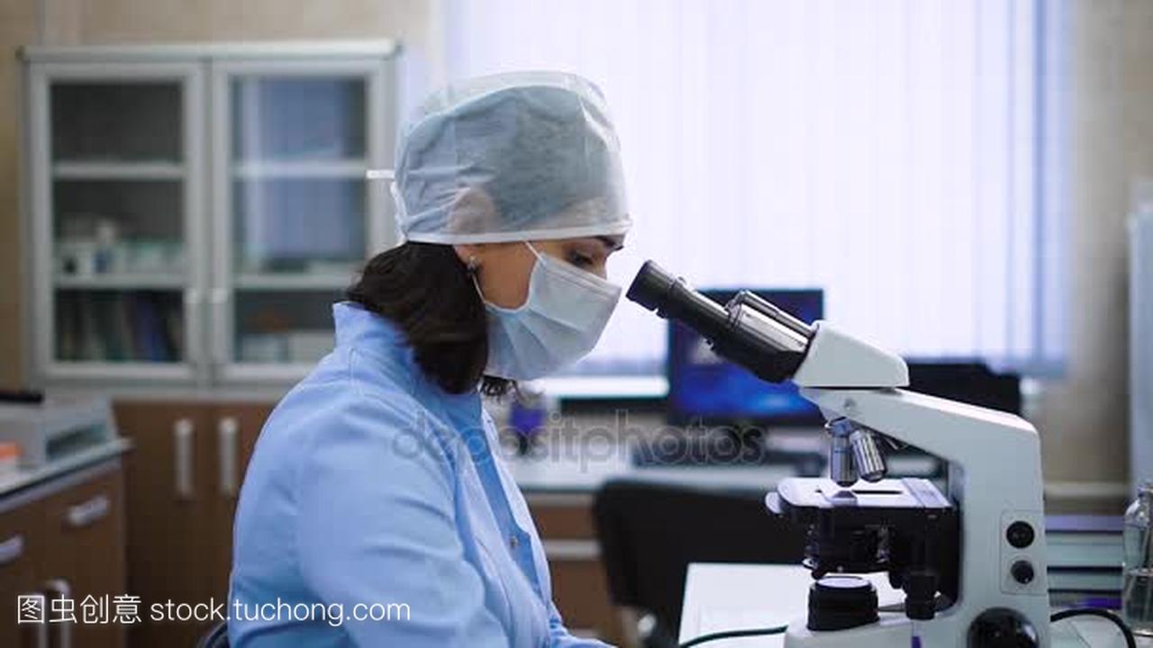 一位穿着蓝色长袍与黑色的短头发女实验室助理