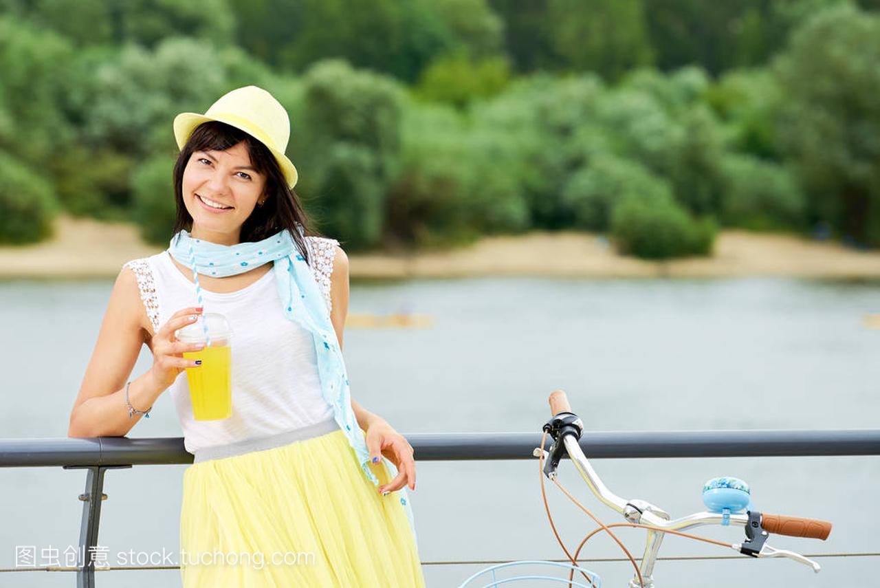 女性喝柠檬水和站在她的自行车的肖像