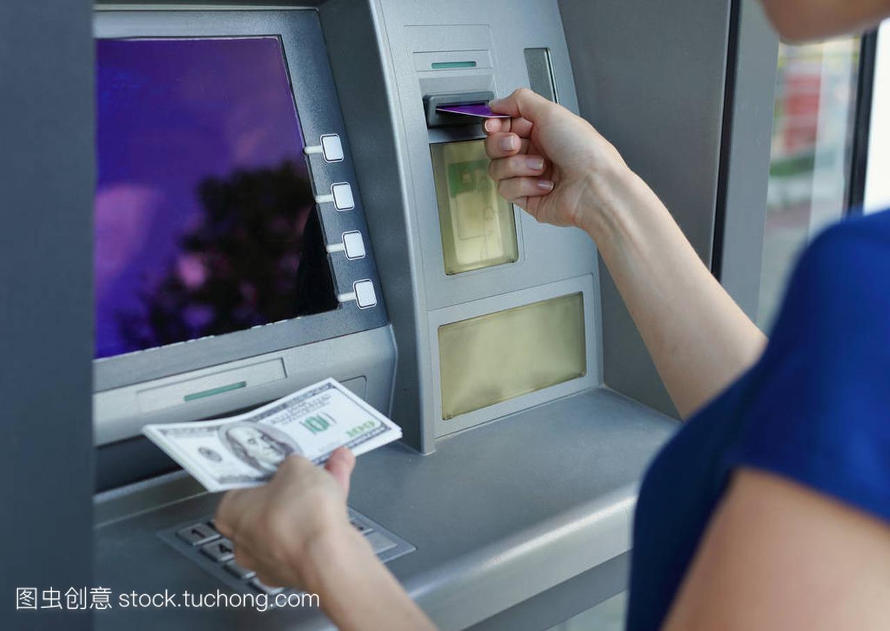 女人从使用信用卡取款机取金钱。现金撤回和财