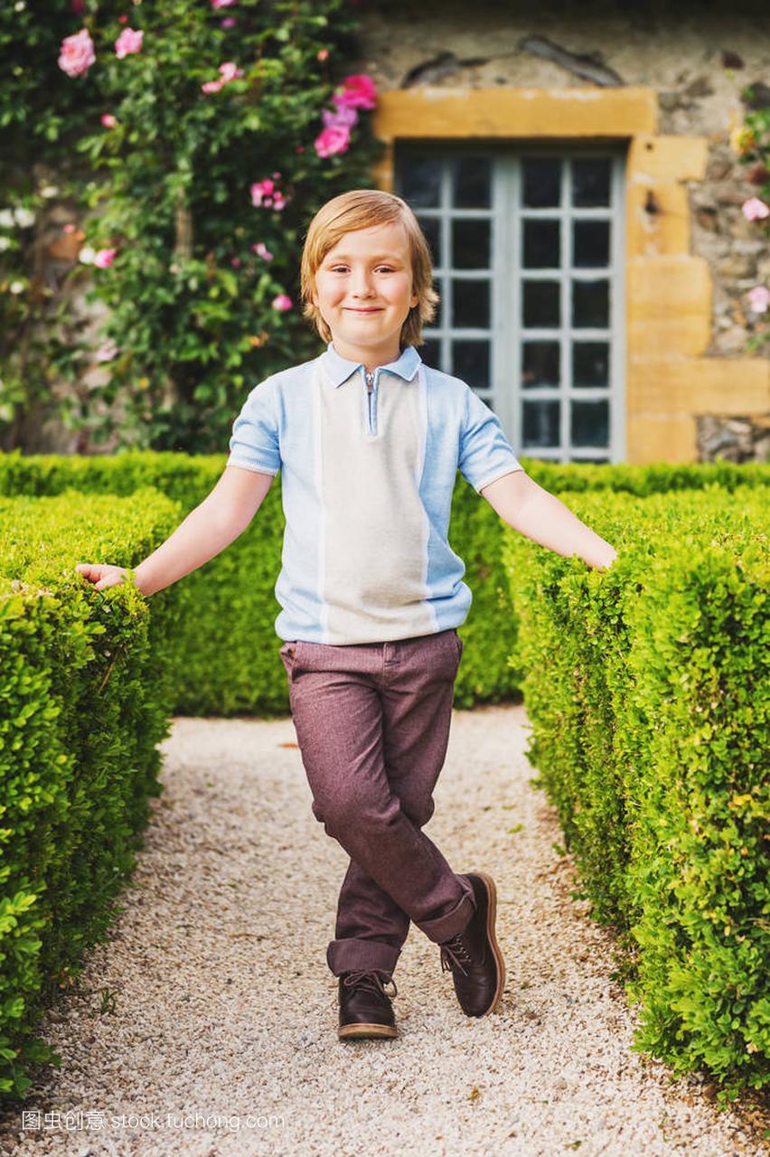 可爱的小男孩摆在古典英语 tapiary 的花园里,穿