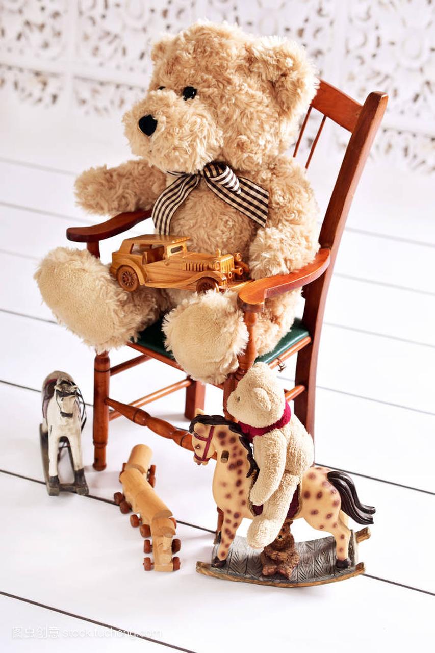 旧的玩具熊坐在椅子上,他的玩具